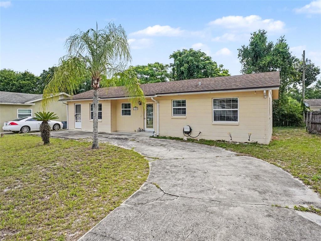 A single-story house with a beige exterior, a concrete driveway, and a palm tree — 1609 MAUREEN AVENUE, OCOEE, FL