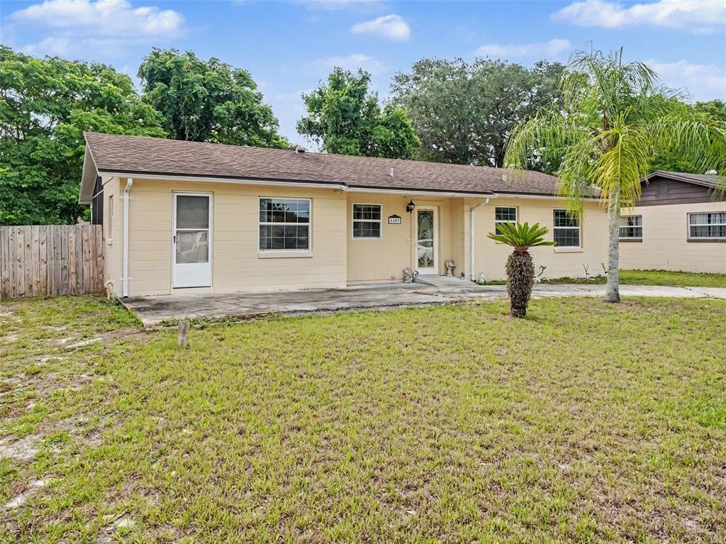 A single-story, light yellow house with a brown roof, concrete patio, and front lawn — 1609 MAUREEN AVENUE, OCOEE, FL