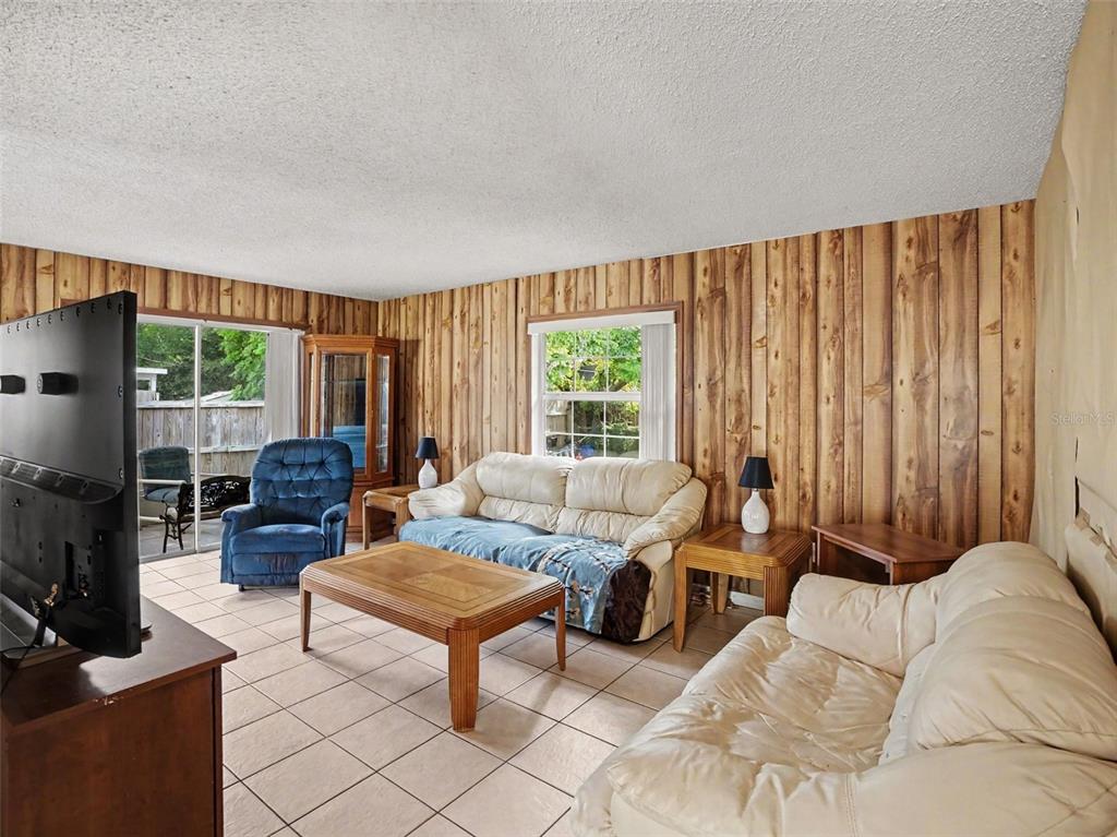A living room features wood-paneled walls, tile flooring, two white sofas, and a blue recliner — 1609 MAUREEN AVENUE, OCOEE, FL