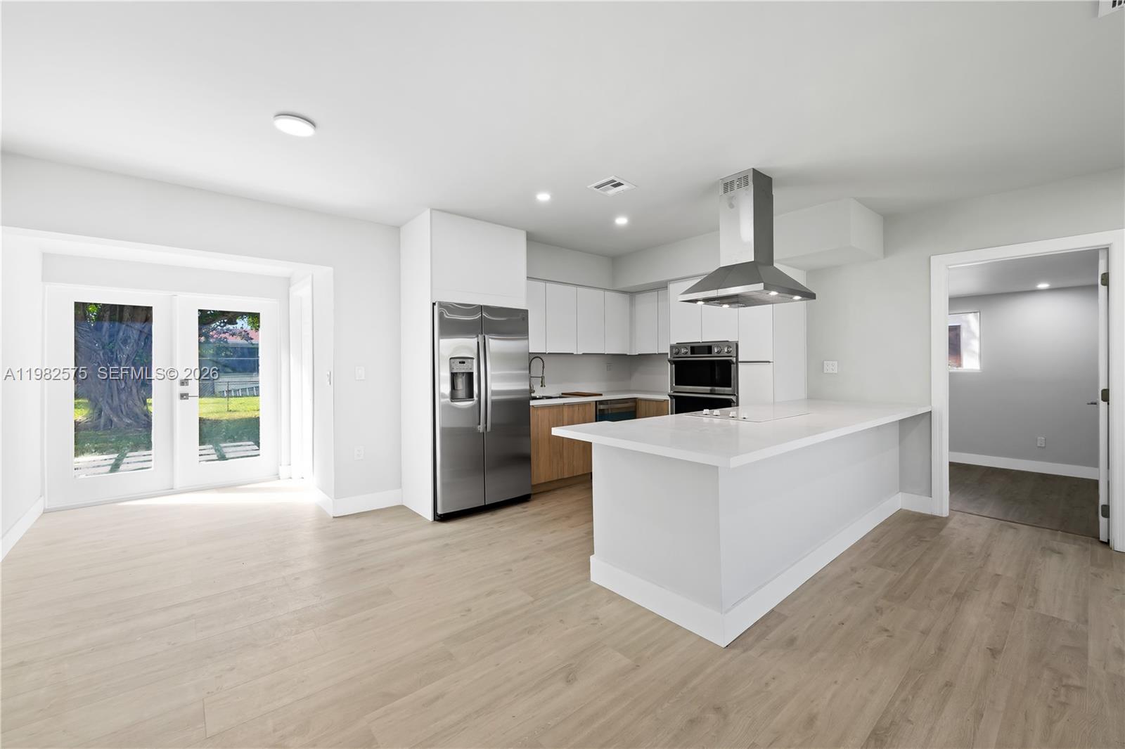 A modern kitchen features white cabinetry, stainless steel appliances, a center island, and light flooring — 8560 SW 126th Ter, Miami FL 33156, MIAMI, FL