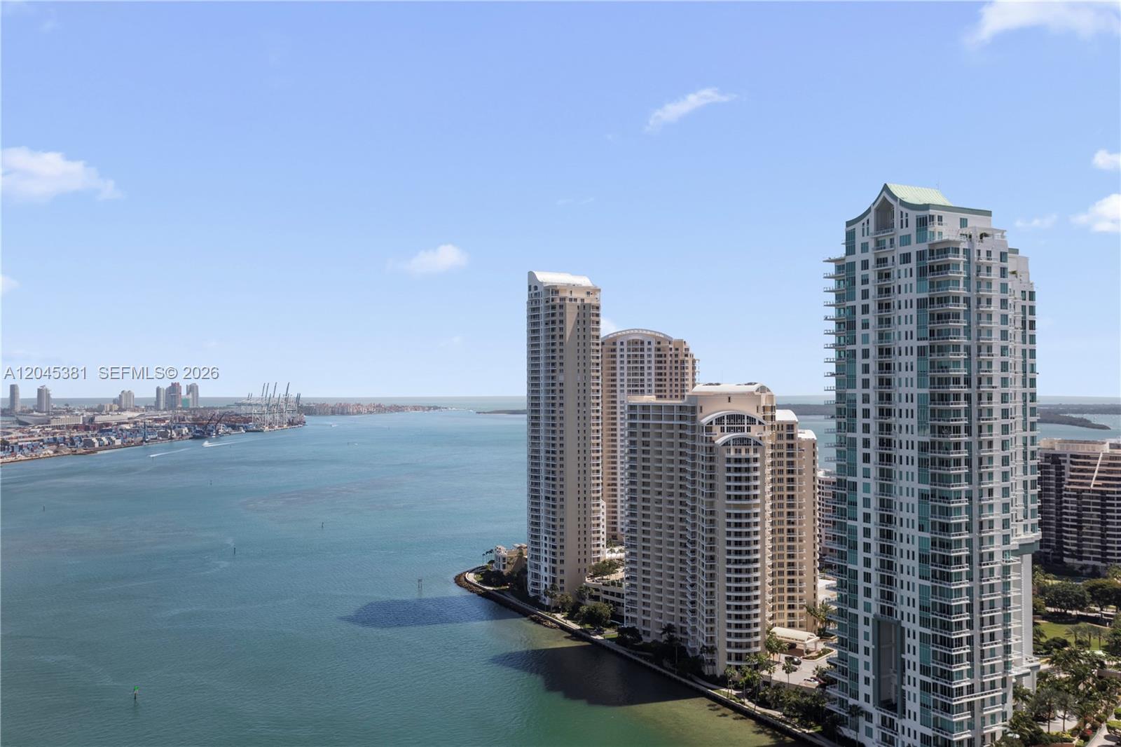 An aerial view shows high-rise residential buildings situated along a waterfront with a shipping port — 300 S Biscayne Blvd # 2806, Miami FL 33131, MIAMI, FL