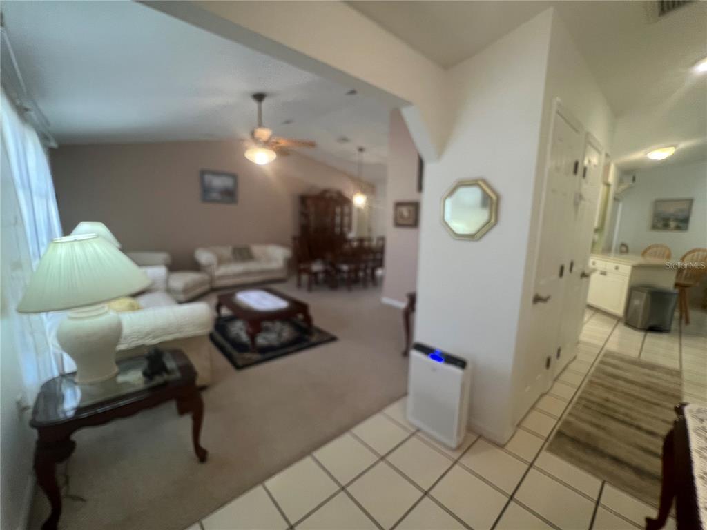 A living room with beige carpet and a dining area visible in the background — 1314 BEACON DRIVE, PORT CHARLOTTE, FL