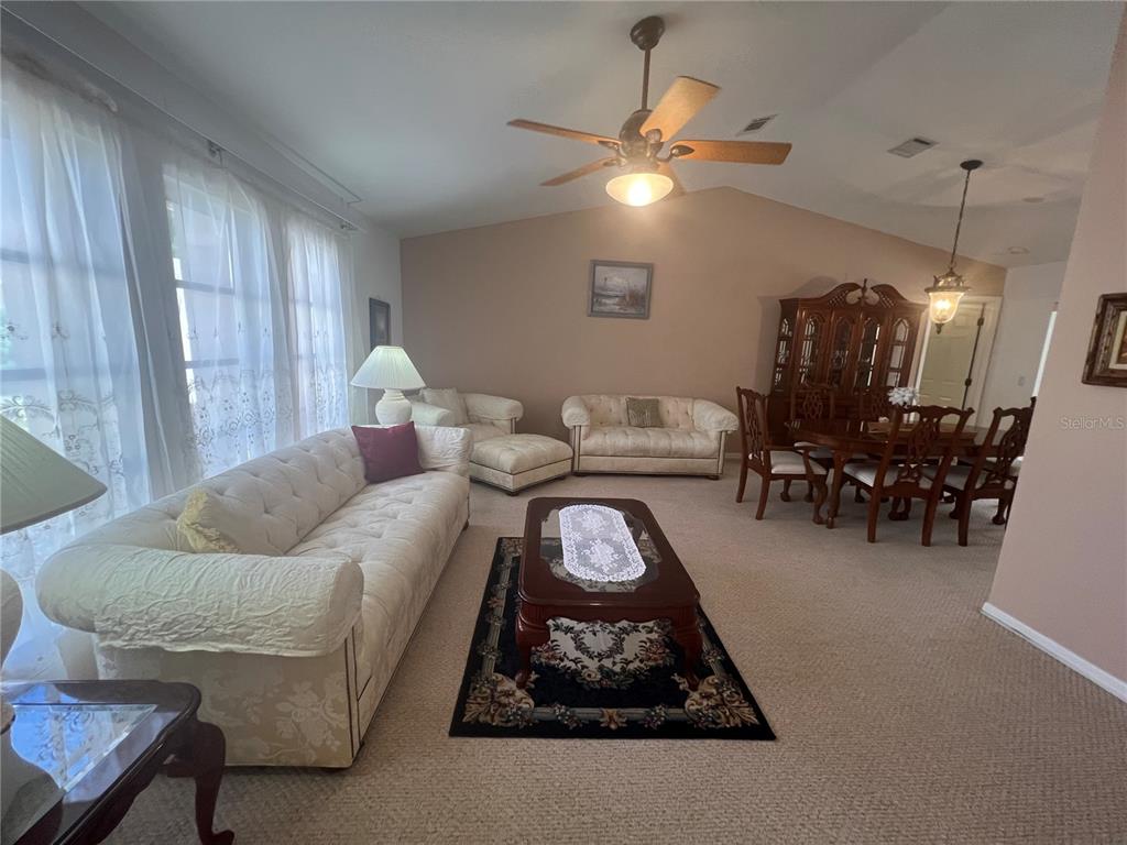 A living and dining room with beige carpet, white sofas, and a wooden dining set — 1314 BEACON DRIVE, PORT CHARLOTTE, FL