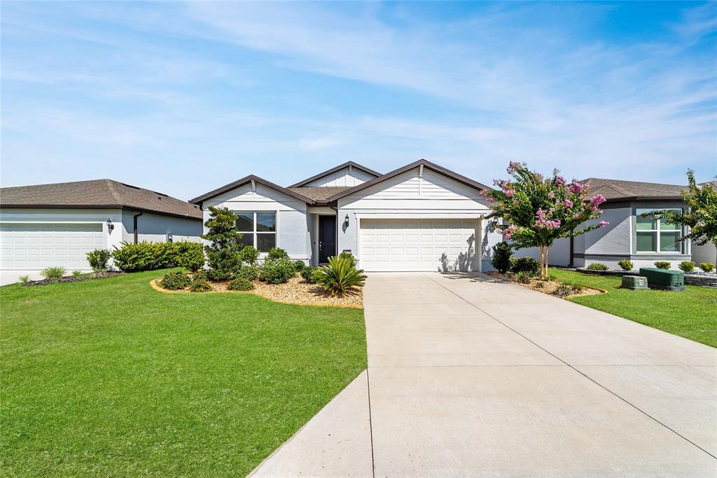 A single-story suburban house with a two-car garage, concrete driveway, and landscaped front yard — 8479 SW 52ND LANE ROAD, OCALA, FL