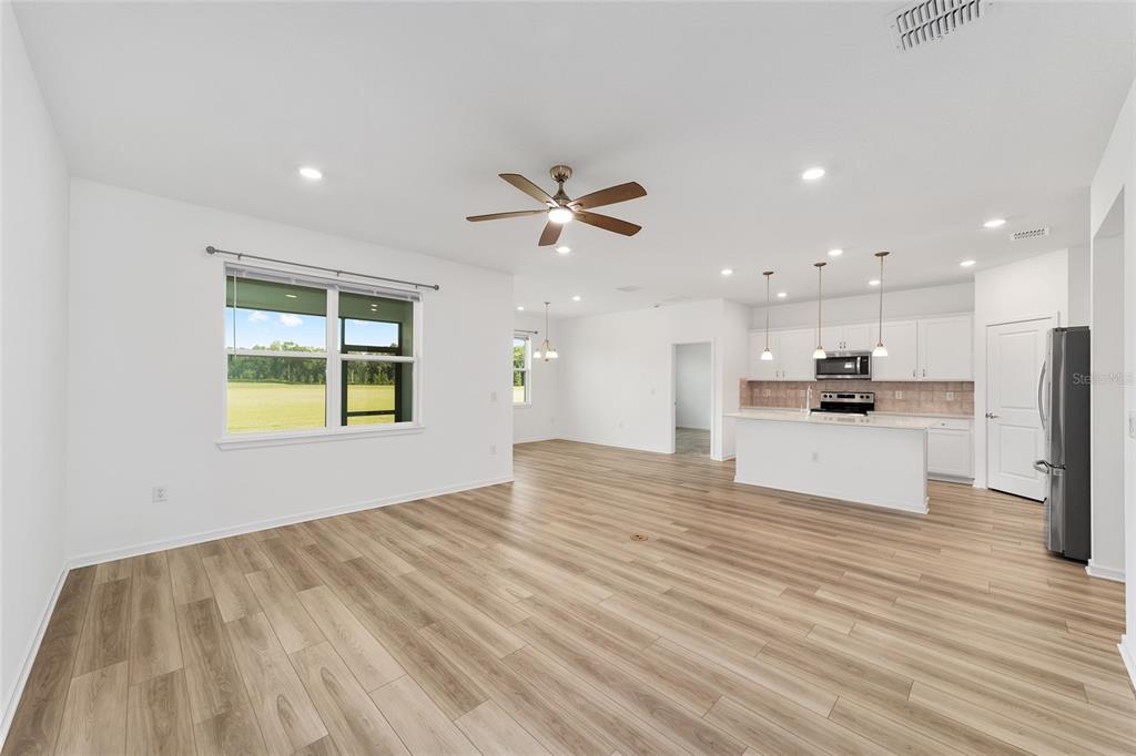 An open-concept living area features light wood-look flooring, white walls, and a kitchen with island — 8479 SW 52ND LANE ROAD, OCALA, FL
