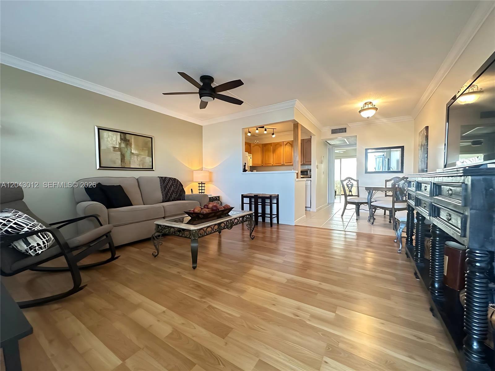 A living room with light wood floors, a sofa, a rocking chair, and an open kitchen — 1009 Harwood C # 1009, Deerfield Beach FL 33442, DEERFIELD BEACH, FL