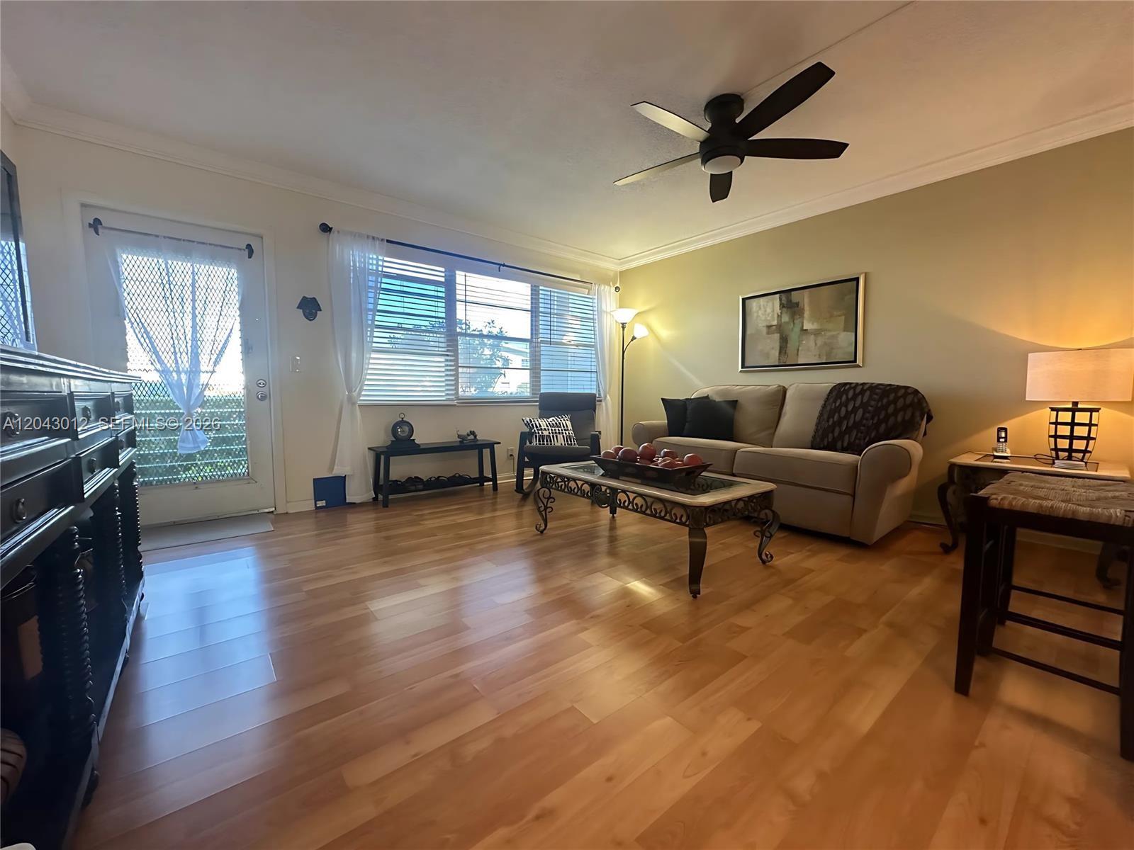 A living room features light wood flooring, a beige sofa, and a ceiling fan — 1009 Harwood C # 1009, Deerfield Beach FL 33442, DEERFIELD BEACH, FL