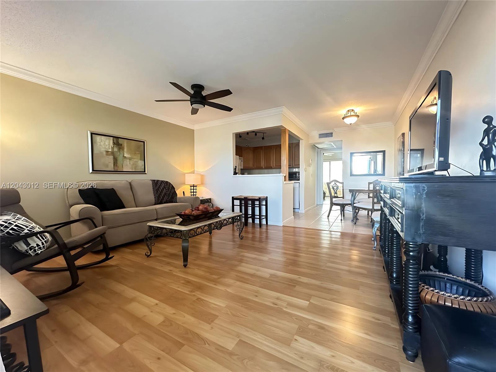 A living room features light wood flooring, a beige sofa, and an open kitchen pass-through — 1009 Harwood C # 1009, Deerfield Beach FL 33442, DEERFIELD BEACH, FL