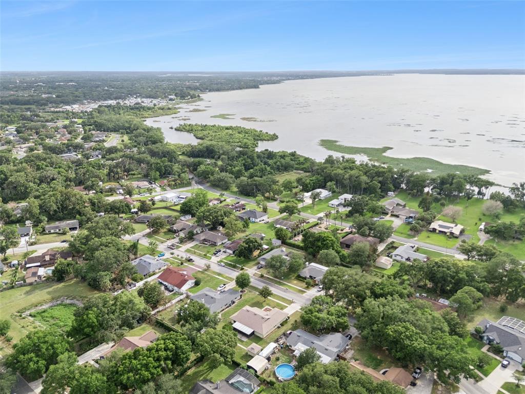 An aerial view shows a suburban neighborhood situated along the shore of a large lake — 1503 COLUSO DRIVE, WINTER GARDEN, FL