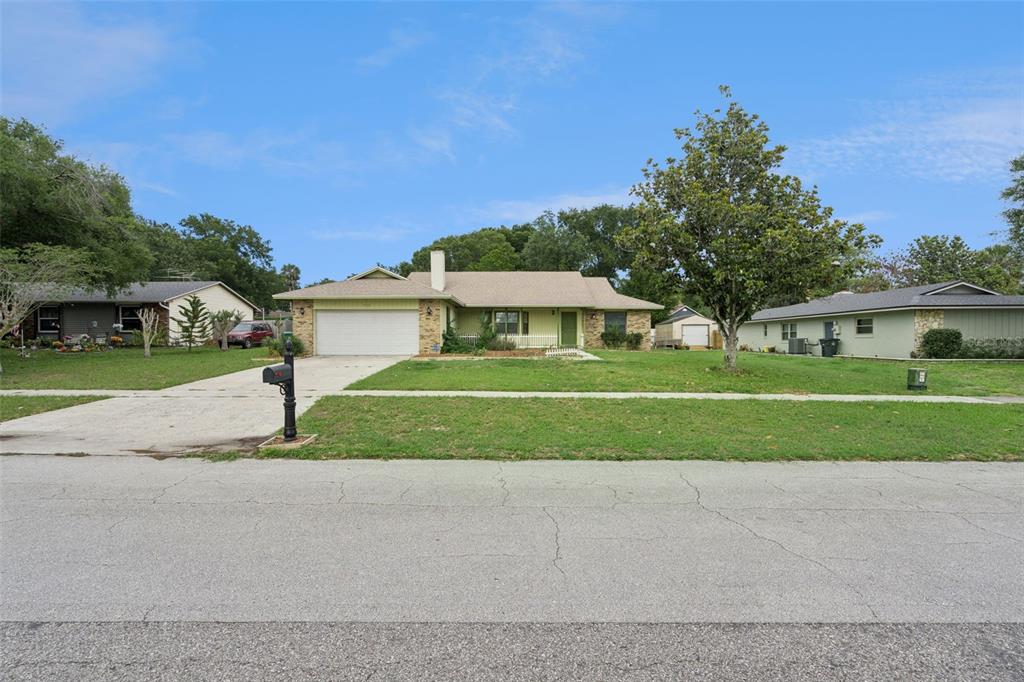 A single-story house with a light green exterior, a two-car garage, and a large lawn — 1503 COLUSO DRIVE, WINTER GARDEN, FL