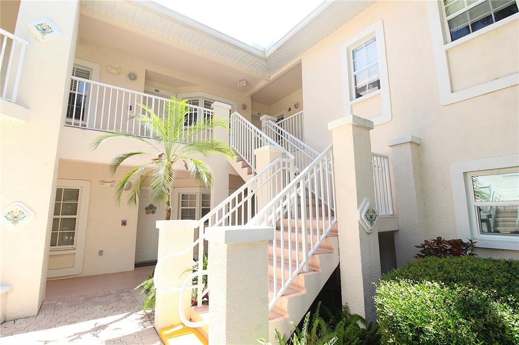 An exterior view of a two-story apartment building with white railings and outdoor stairs — 4260 CENTRAL SARASOTA PARKWAY UNIT 224, SARASOTA, FL