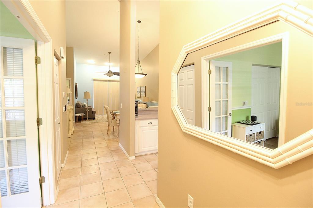 A tiled hallway leads to an open living area with a mirror on the wall — 4260 CENTRAL SARASOTA PARKWAY UNIT 224, SARASOTA, FL