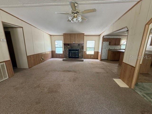 A living room features beige carpet, wood-paneled walls, a stone fireplace, and a ceiling fan — 18627 NW 24TH AVENUE, CITRA, FL