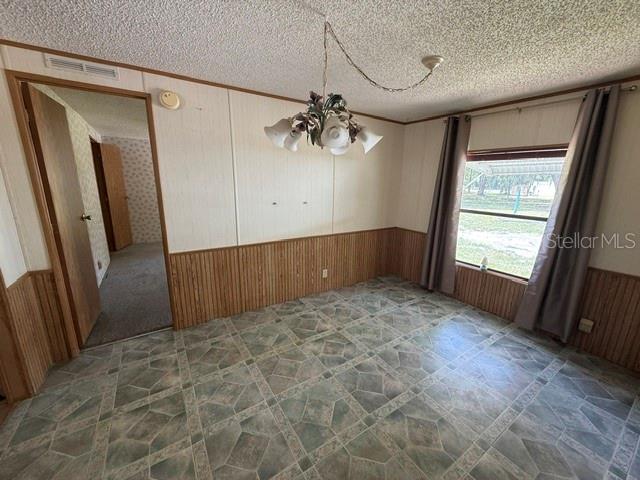A dining room with wood paneling, patterned vinyl flooring, a chandelier, and a window with curtains — 18627 NW 24TH AVENUE, CITRA, FL