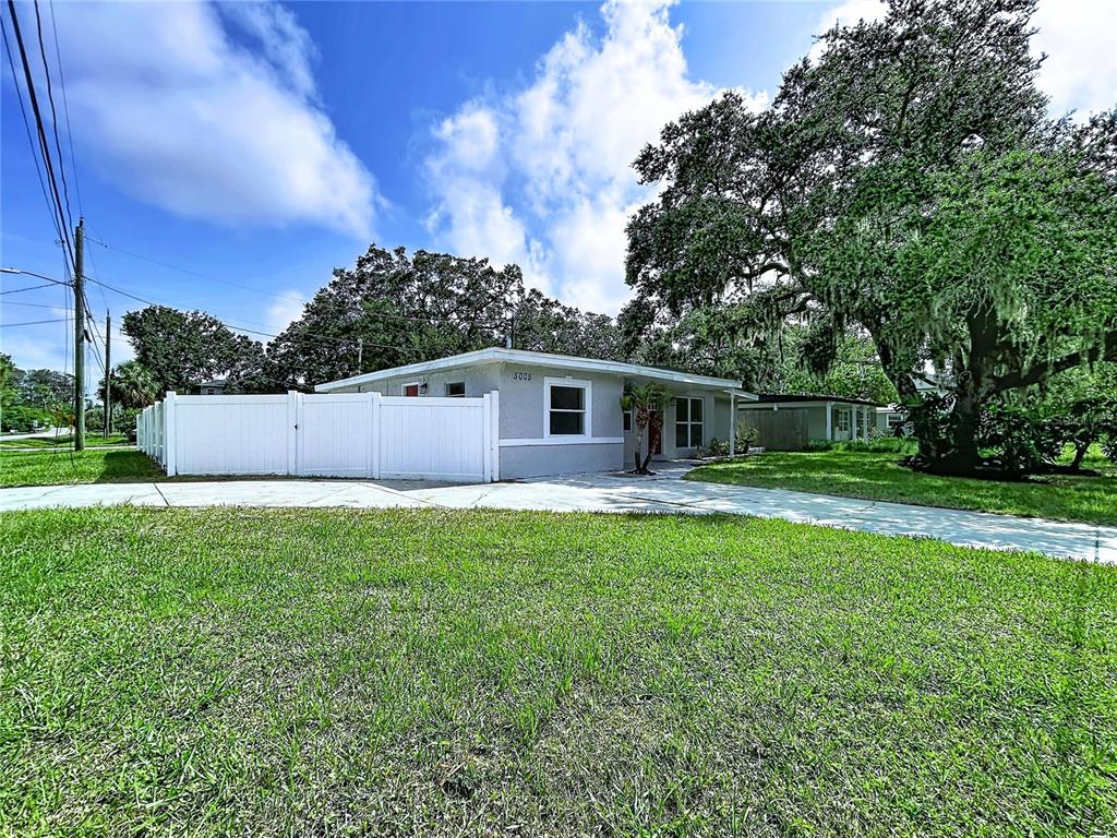 A single-story house with a white fence and a large tree in the front yard — 5005 AVERY ROAD, NEW PORT RICHEY, FL