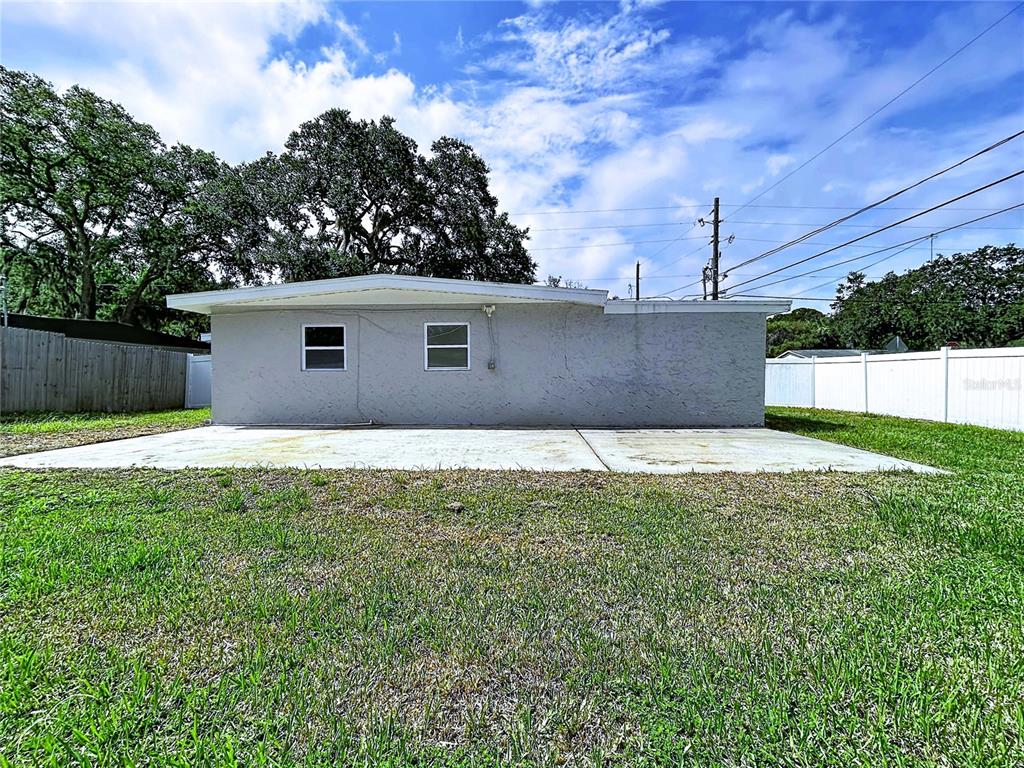 The exterior of a single-story house features a concrete patio and a white vinyl fence — 5005 AVERY ROAD, NEW PORT RICHEY, FL