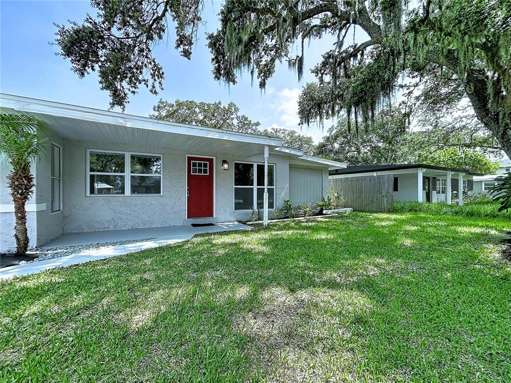 A single-story house with a red front door, a covered porch, and a grassy yard — 5005 AVERY ROAD, NEW PORT RICHEY, FL