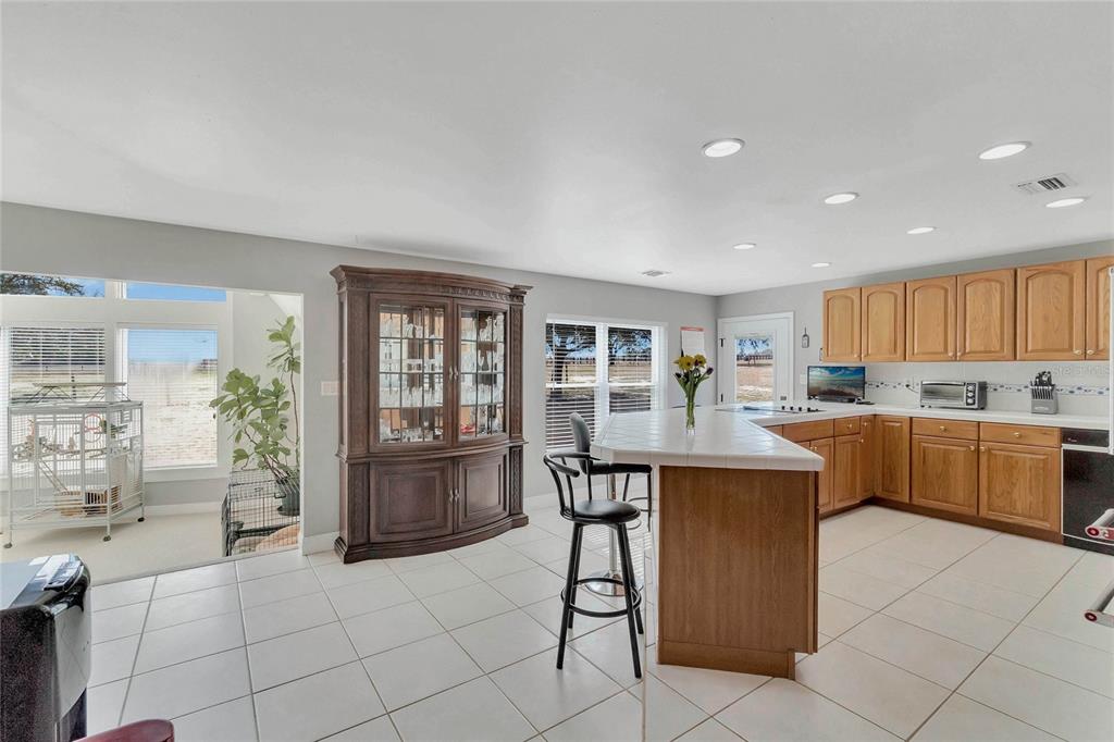 A kitchen with light tile floors, oak cabinets, a tiled island, and a large hutch — 16131 JOHNS LAKE ROAD, CLERMONT, FL