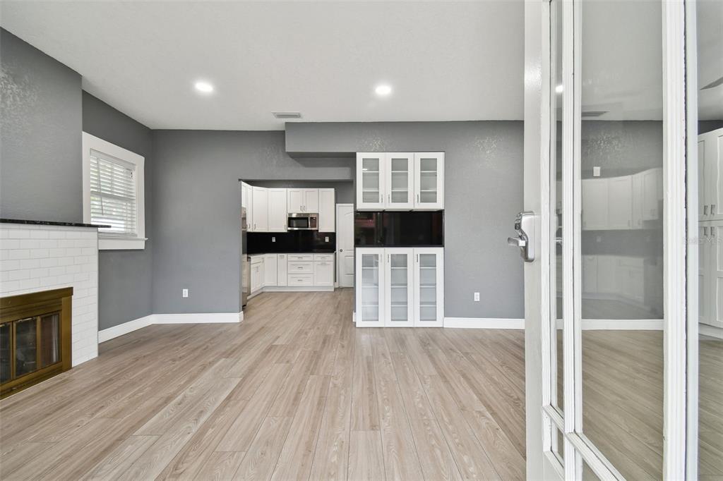 A living room with gray walls, wood-look flooring, a fireplace, and a built-in cabinet unit — 6810 N NAVIN AVENUE, TAMPA, FL