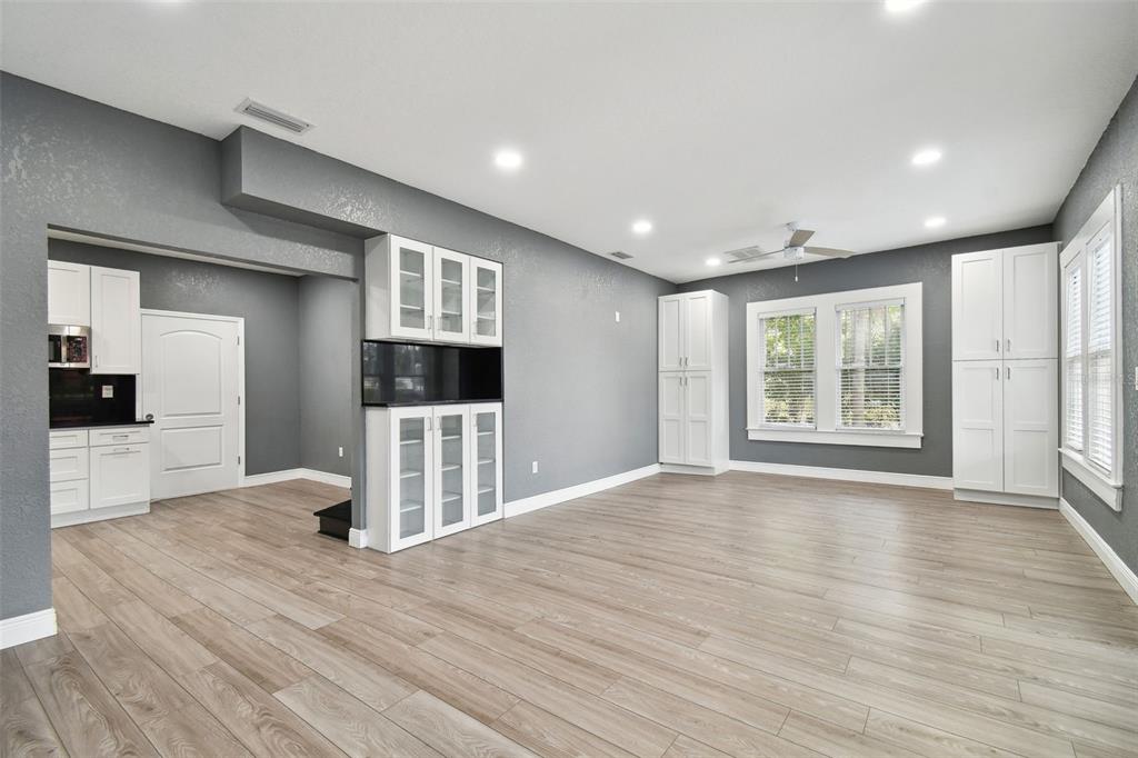 A spacious room with grey walls, light wood flooring, and white built-in cabinetry — 6810 N NAVIN AVENUE, TAMPA, FL