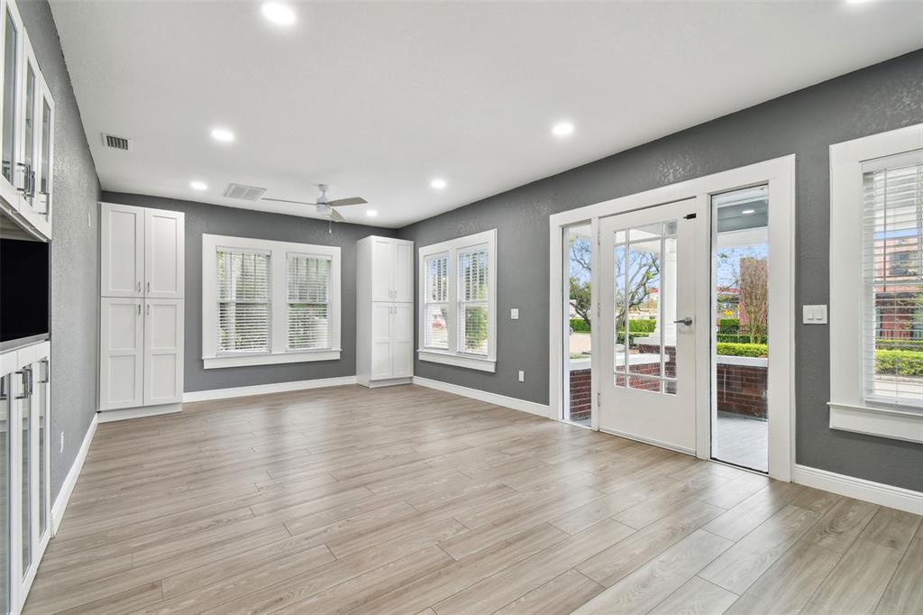 A living room features gray walls, light wood-look flooring, white cabinetry, and a glass door — 6810 N NAVIN AVENUE, TAMPA, FL