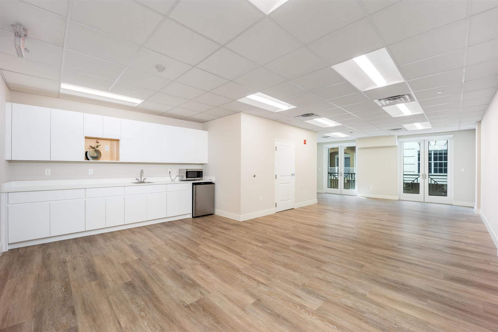 A bright office breakroom features white cabinetry, a small kitchenette, and light wood-look flooring — 41 SW Seminole Street # 211, Stuart FL 34994, STUART, FL