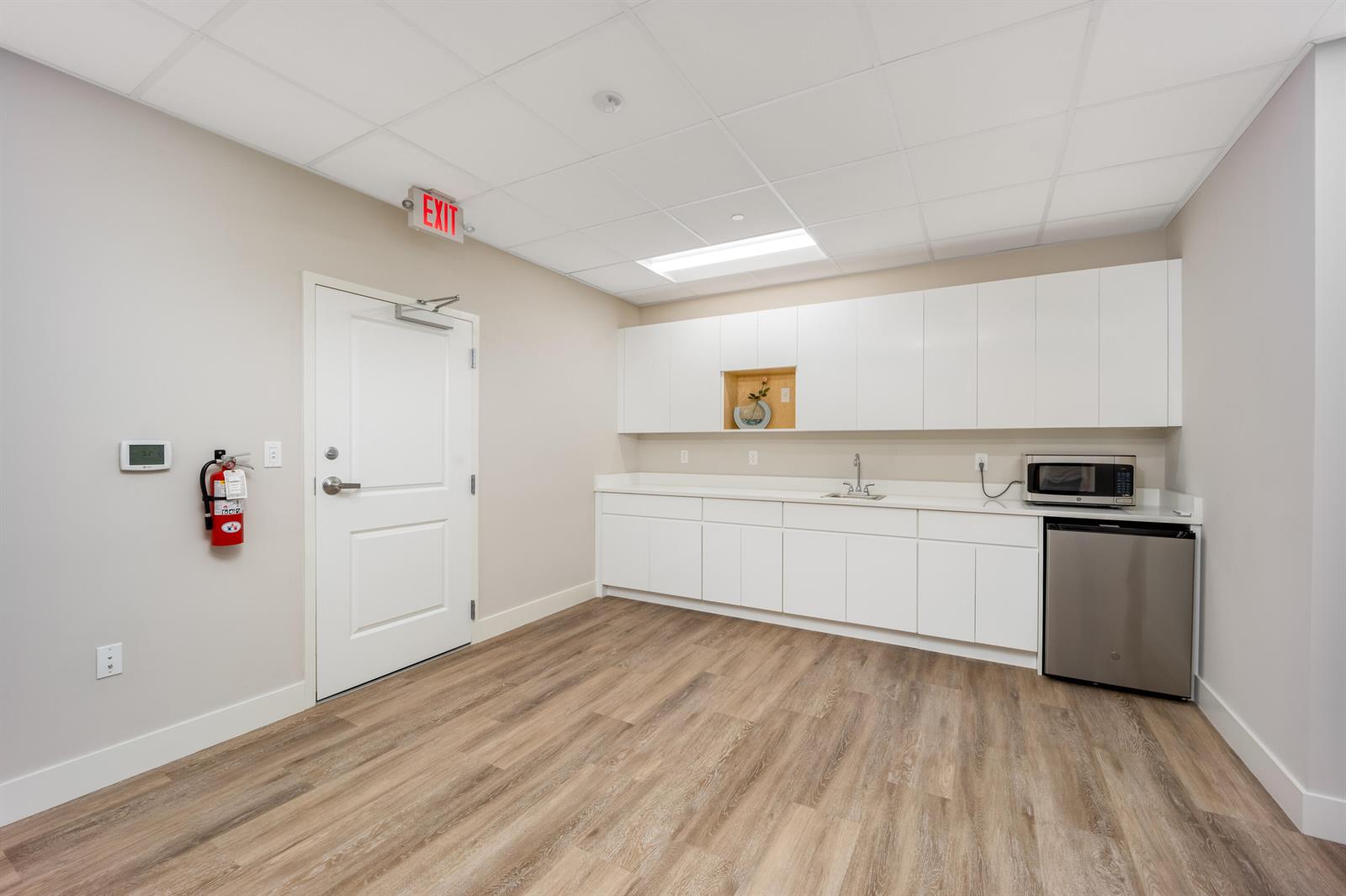 A breakroom features white cabinetry, a stainless steel microwave, a mini-fridge, and wood-look flooring — 41 SW Seminole Street # 211, Stuart FL 34994, STUART, FL