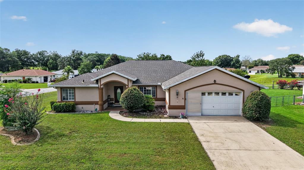 A single-story suburban house with a tan stucco exterior, a gray roof, and a garage — 10121 SW 61ST TERRACE ROAD, OCALA, FL