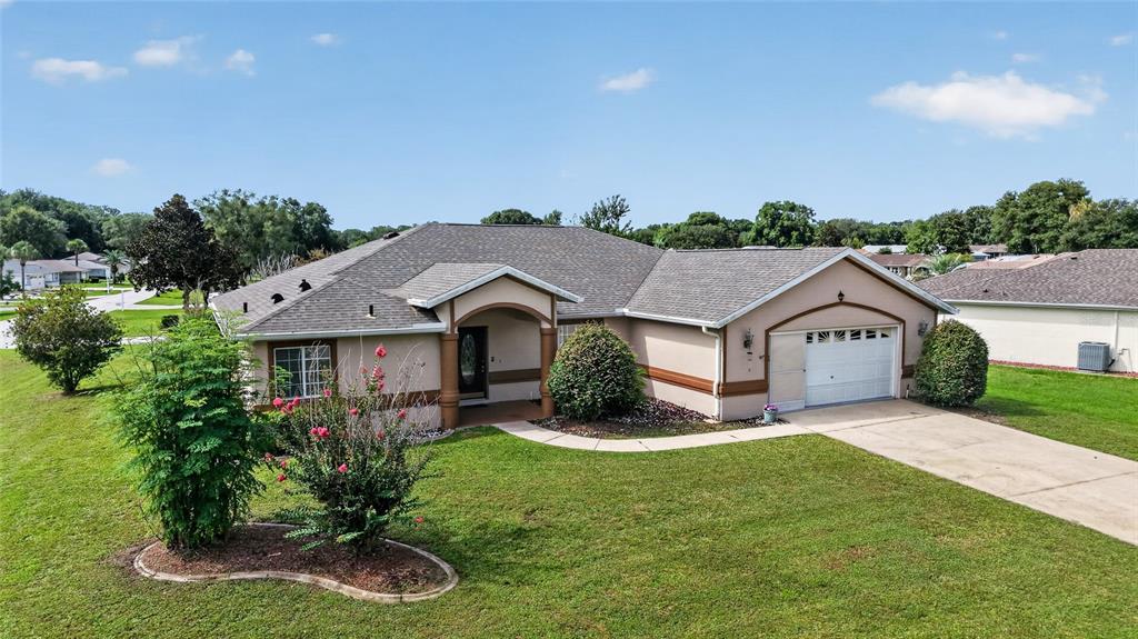 A single-story house with a tan stucco exterior, a gray shingled roof, and a driveway — 10121 SW 61ST TERRACE ROAD, OCALA, FL
