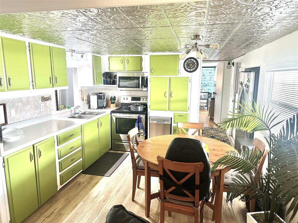 A kitchen features lime green cabinets, a metallic patterned ceiling, and a wooden dining table — 9790 66TH STREET N UNIT 144, PINELLAS PARK, FL