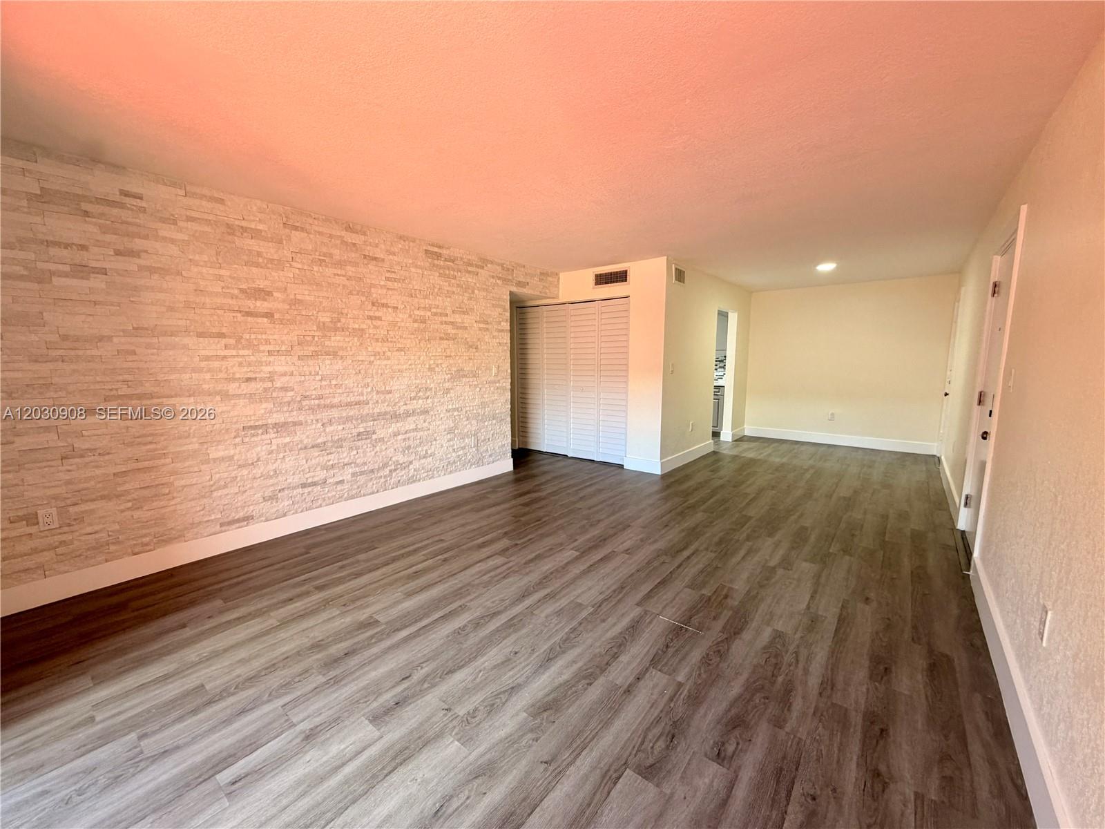 This living room features a textured stone accent wall and wood-look vinyl flooring — MIAMI LAKES, FL