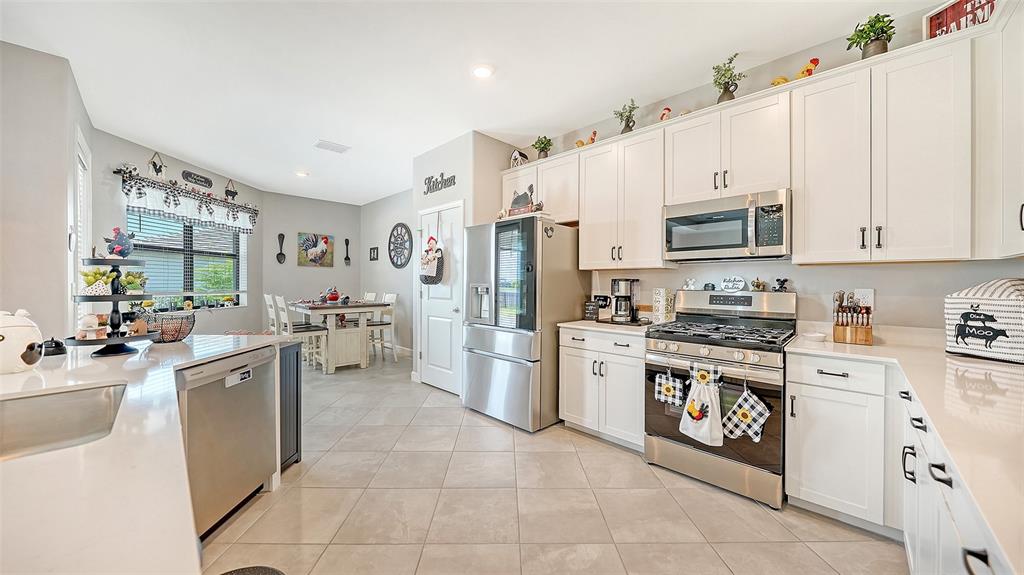 A kitchen features white cabinets, stainless steel appliances, and a dining area with a table — 4971 OYSTER PEARL STREET, BRADENTON, FL