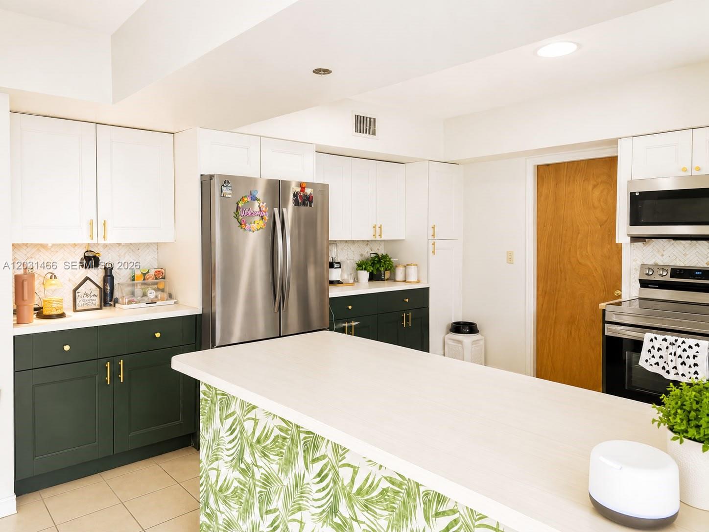 A kitchen features white upper cabinets, dark green lower cabinets, and a palm-print kitchen island — 12601 Stirling Rd, Southwest Ranches FL 33330, SOUTHWEST RANCHES, FL
