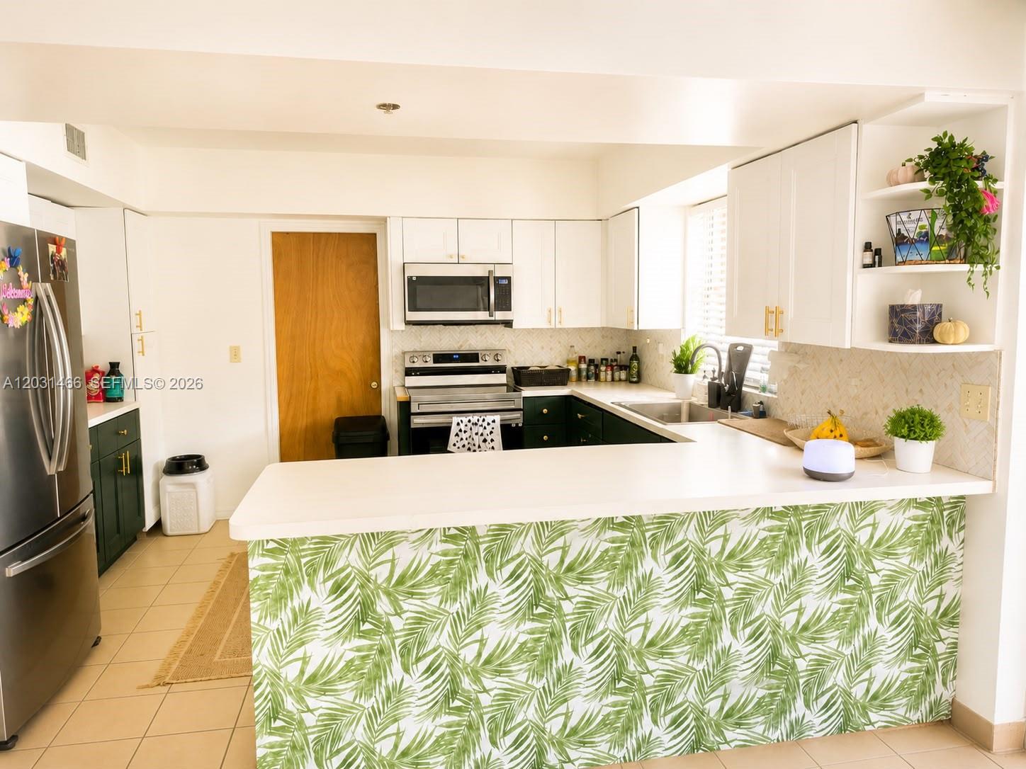 A kitchen features white upper cabinets, dark green lower cabinets, and a palm-print breakfast bar — 12601 Stirling Rd, Southwest Ranches FL 33330, SOUTHWEST RANCHES, FL