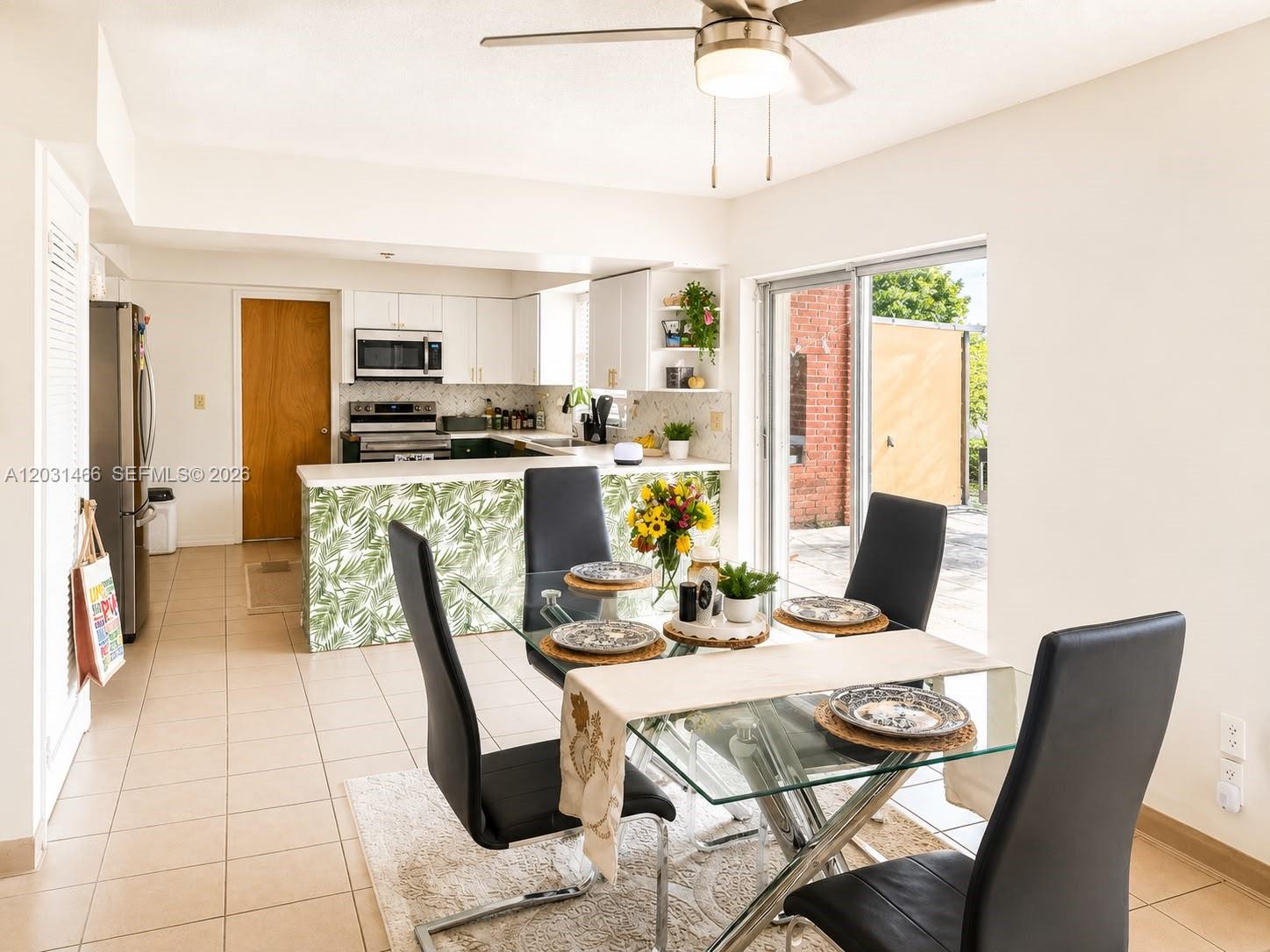 A dining area with a glass table and black chairs sits adjacent to a kitchen — 12601 Stirling Rd, Southwest Ranches FL 33330, SOUTHWEST RANCHES, FL