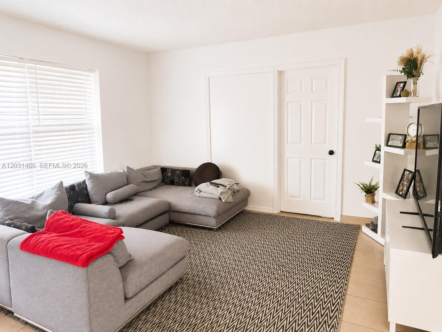 A living room features a gray sectional sofa, a patterned area rug, and white shelving — 12601 Stirling Rd, Southwest Ranches FL 33330, SOUTHWEST RANCHES, FL