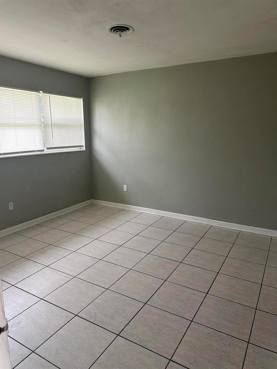 An empty room with light gray walls, white trim, and light-colored square floor tiles — 3194 Prince Drive # 3196, Lake Worth FL 33461, LAKE WORTH, FL