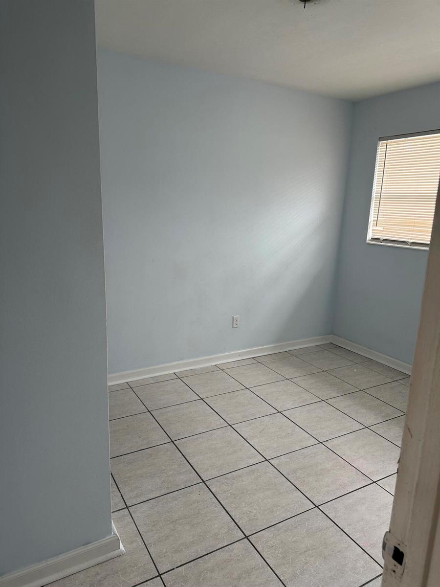 An empty room features light blue walls, a window with blinds, and light-colored tile flooring — 3194 Prince Drive # 3196, Lake Worth FL 33461, LAKE WORTH, FL