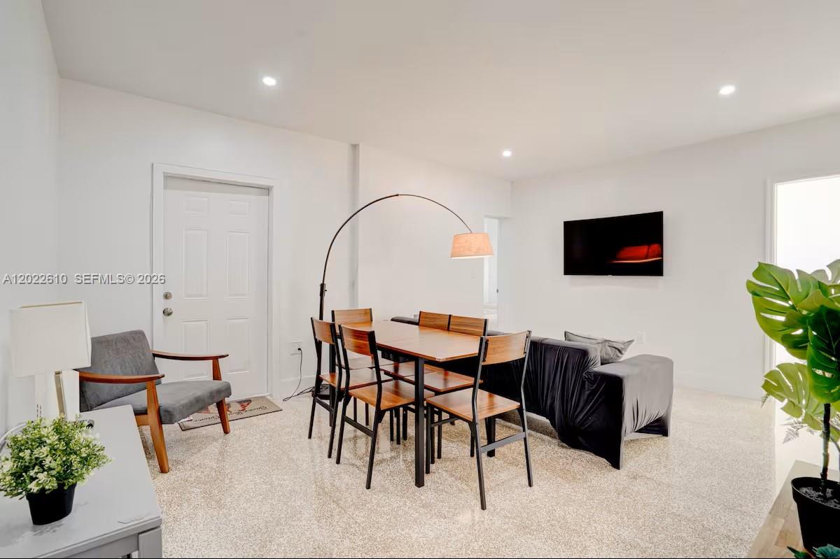 A dining area and living space feature white walls, light flooring, and modern furniture — 224 NE 111th St, Miami FL 33161, MIAMI, FL