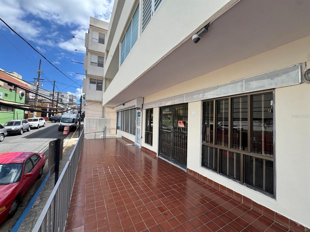 A tiled walkway leads to the entrance of a commercial building with large glass windows — 17 NC PERAL UNIT 1B, MAYAGUEZ, PR