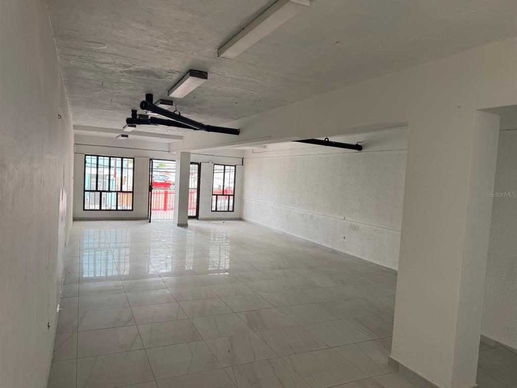 An empty commercial space features white tiled floors, white walls, and exposed ceiling fixtures — 17 NC PERAL UNIT 1B, MAYAGUEZ, PR