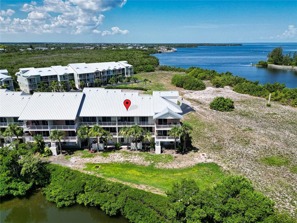 An aerial view shows a multi-story residential building with a metal roof near water — 3273 MANGROVE POINT DRIVE, RUSKIN, FL