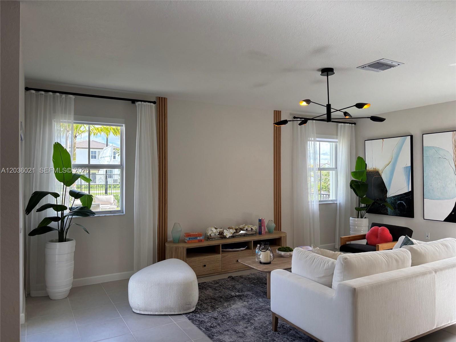 A living room features a white sofa, a wooden media console, and a modern chandelier — 2342 SE 30th St, Homestead FL 33035, HOMESTEAD, FL
