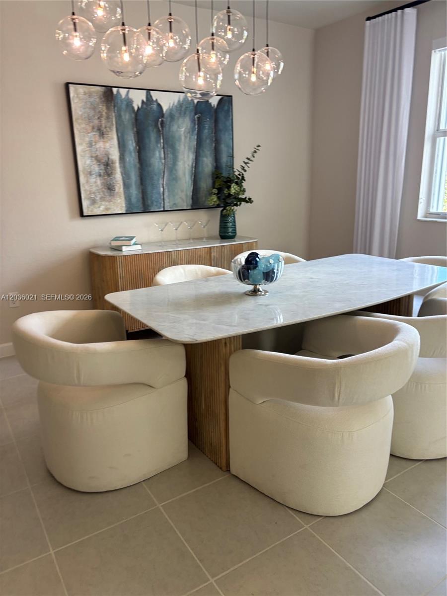 A dining room features a marble-topped table, curved cream chairs, and a modern globe chandelier — 2342 SE 30th St, Homestead FL 33035, HOMESTEAD, FL