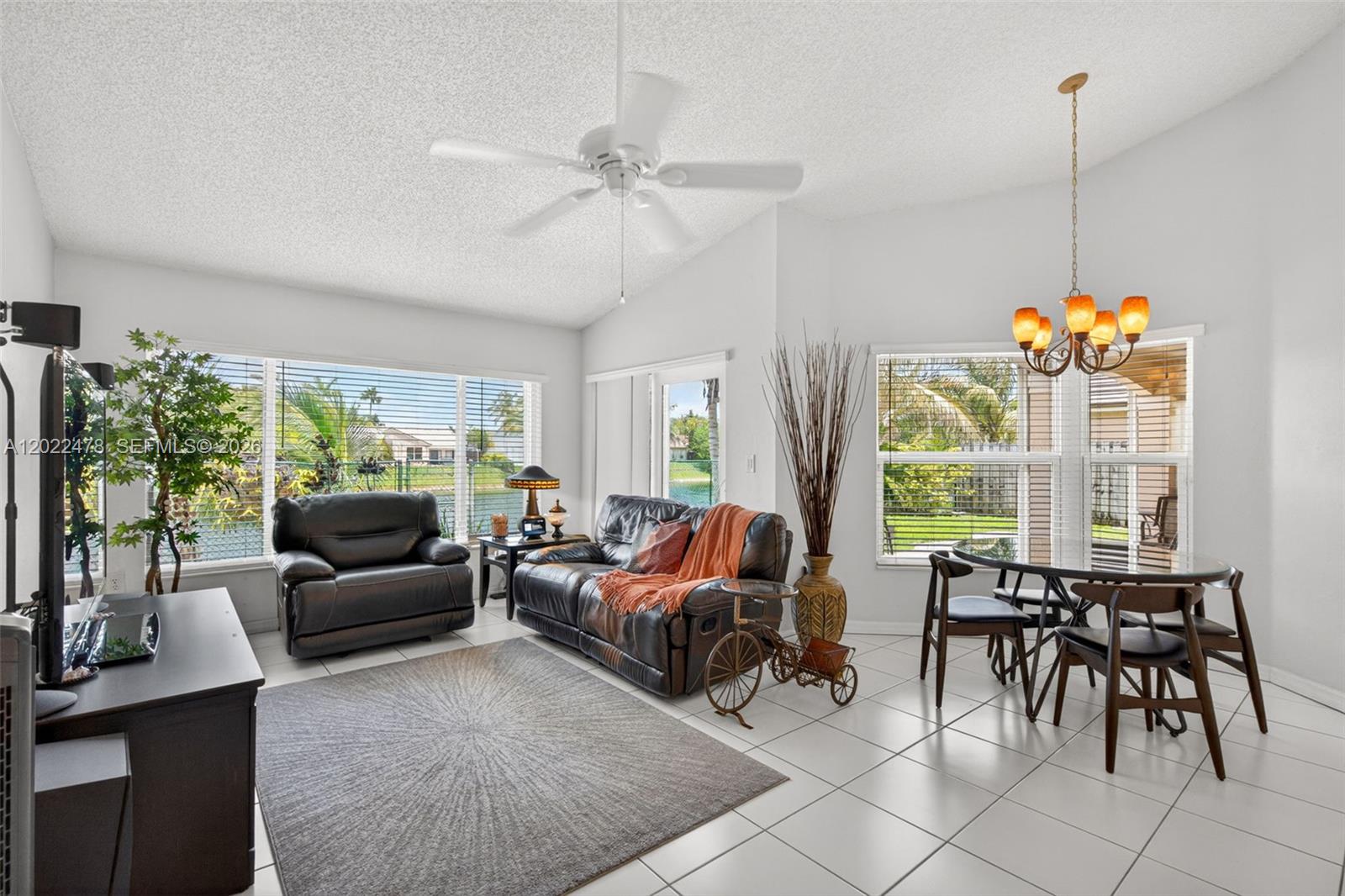 A living and dining area with white tile floors, a ceiling fan, and large windows — 15891 SW 84th St, Miami FL 33193, MIAMI, FL