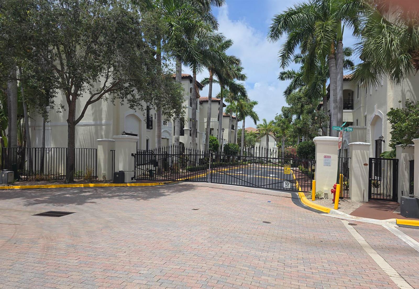 A gated entrance with palm trees leads to a multi-story apartment complex — 1602 Coastal Bay Boulevard, Boynton Beach FL 33435, BOYNTON BEACH, FL