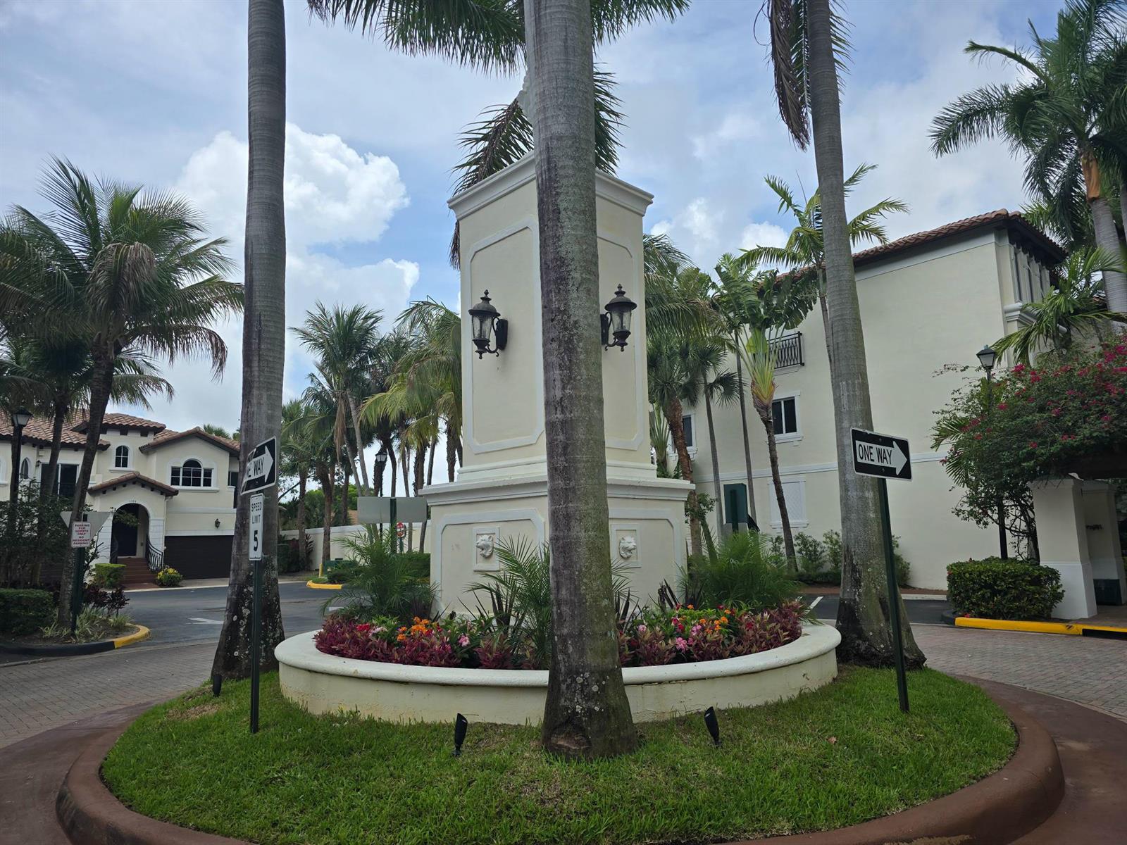 A central stone monument sits in a landscaped roundabout surrounded by palm trees and buildings — 1602 Coastal Bay Boulevard, Boynton Beach FL 33435, BOYNTON BEACH, FL