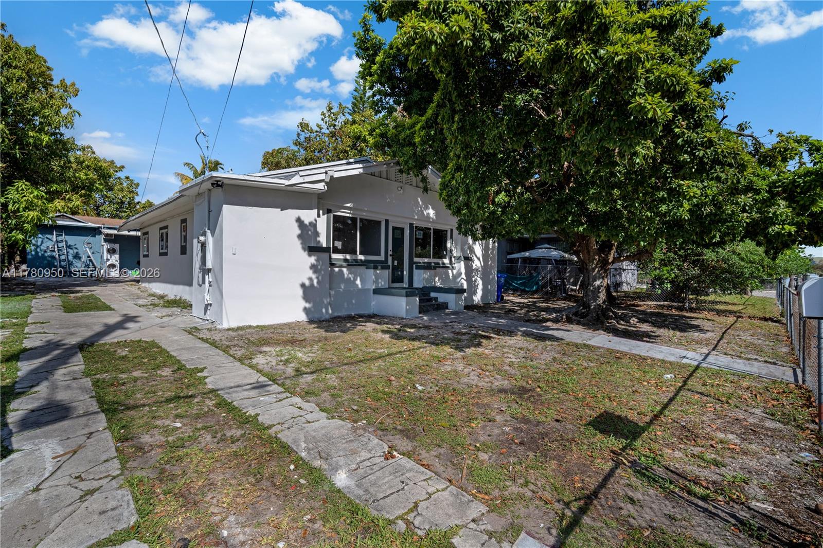 A white single-story house features a concrete walkway and a large tree in the yard — 1114 SW 13th Ct, Miami FL 33135, MIAMI, FL