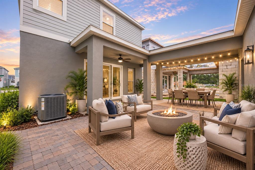 A paved patio features a fire pit, outdoor seating, and a covered dining area at sunset — 13043 SERENE GLADE ROAD, WINTER GARDEN, FL