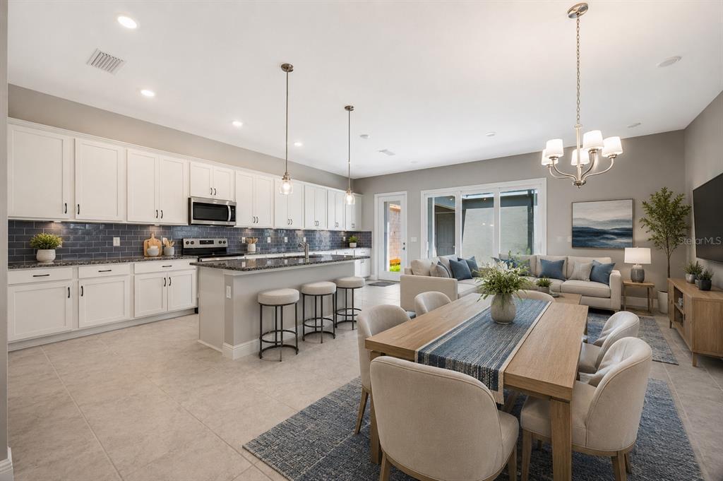 An open-concept kitchen and dining area features white cabinetry, a kitchen island, and tile flooring — 13043 SERENE GLADE ROAD, WINTER GARDEN, FL